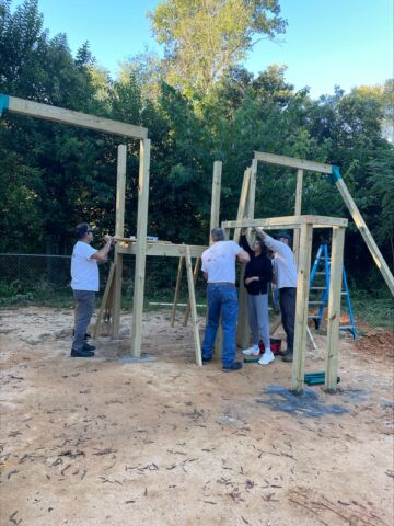 Group of people help to assemble the play house structure.